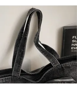 Detail view of denim tote bag with contrast stitching and metal zipper closure