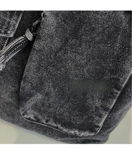 Detail of washed black denim fabric with visible stitching and distressed pocket edges