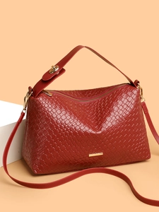 Detailed close-up of dark red woven leather bag texture with shiny gold hardware accents