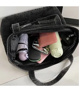 Top view of spacious interior of black denim tote bag with daily essentials inside