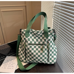 Detail of green checkerboard tote bag with multiple zipper pockets and wide strap