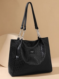 Detail of black woven PU tote bag with silver chain strap and metal logo plate