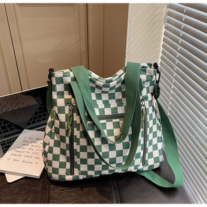 Close-up of green checkered tote bag with corduroy texture and front zipper pockets
