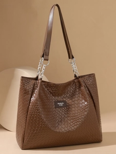 Detail of deep brown woven texture tote bag featuring silver chain link and leather handle