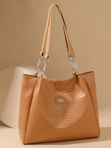 Detail of woven faux leather texture and silver chain strap on caramel tote bag