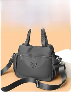 Detail of grey nylon handbag with adjustable strap and front zipper pocket close-up