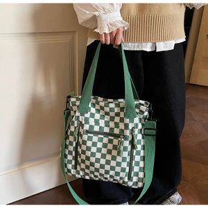 Detail of green checkerboard canvas tote bag featuring triple front zipper pockets