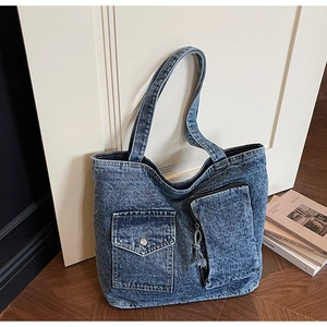 Close-up of retro blue denim tote bag featuring dual front pockets and wide straps