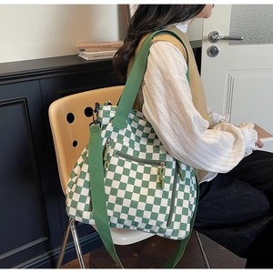 Detail of green checkerboard tote bag with adjustable strap and functional side zip pocket