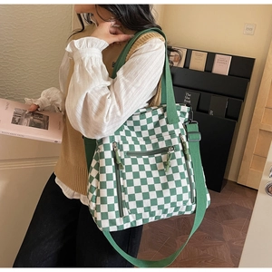 Detail of green checkerboard tote bag with multiple zipper pockets and wide strap