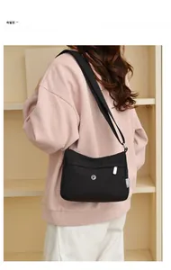 Rear view of model wearing a black lightweight nylon crossbody bag with adjustable strap