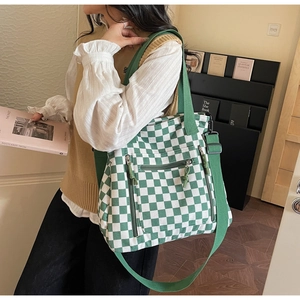 Detail of green checkerboard tote with three functional zipper pockets and wide shoulder strap