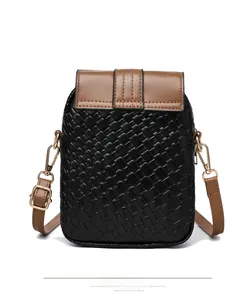 Close-up of black woven texture and brown leather flap on small crossbody bag
