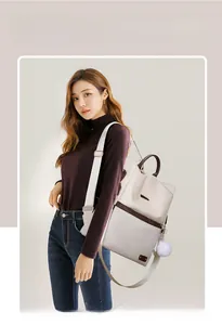Dettaglio zaino in tessuto Oxford beige con finiture marroni e ciondolo a pompon morbido