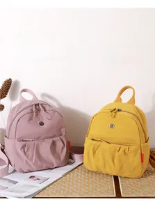 Close-up of pink and yellow canvas backpacks with pleated details and side pockets