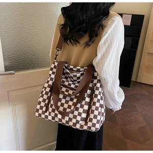 Detail of checkered tote bag with adjustable brown strap and side zipper pocket