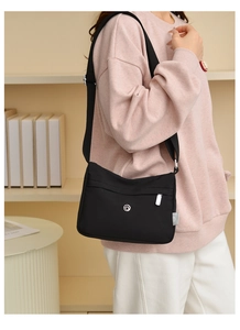Detail of black nylon crossbody bag featuring adjustable strap and silver metal zippers