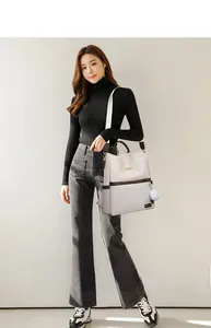 Modella asiatica con zaino in tessuto Oxford beige, finiture marroni e pompon bianco
