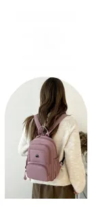 Rear view of model wearing a multifunctional mauve nylon backpack with multiple compartments