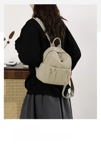 Detail view of the pleated front pocket and red tag on this beige Oxford canvas backpack