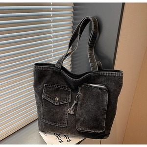 Detail of grey washed denim tote bag showing metal buckle pocket and precise stitching