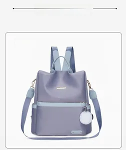 Dettaglio zaino grigio in tessuto Oxford con tasche laterali e ciondolo a pompon