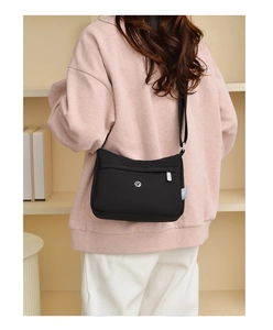 Detailed back view of a black nylon crossbody bag with adjustable wide strap and metal logo