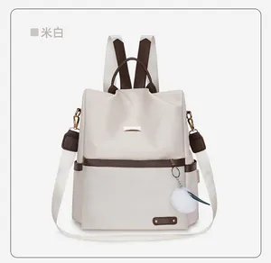 Dettaglio frontale dello zaino in tessuto Oxford bianco crema con pon pon decorativo