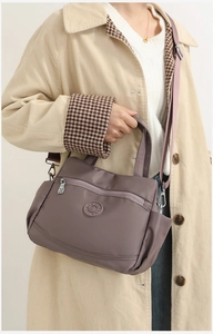 Detail of purple-grey nylon multi-layer handbag with detachable strap on model