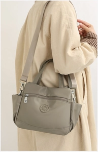 Detail view of khaki nylon multi-layer crossbody bag featuring a round embossed logo