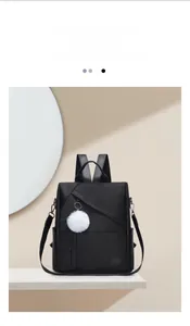 Detail of minimalist black oxford backpack with soft puff keychain and side pocket