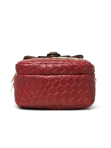 Close-up of a woven red crossbody bag with golden logo and brown bow decoration