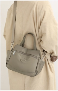 Detail view of khaki nylon crossbody bag with multi-zipper pockets on corduroy coat