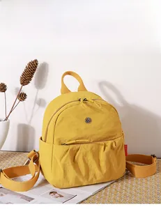 Macro detail of a bright yellow nylon backpack featuring a unique pleated pocket and red tag