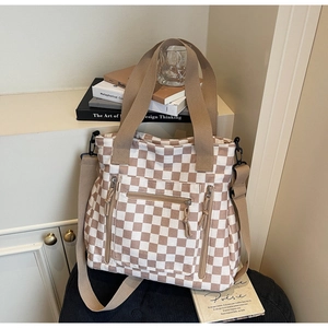 Detail view of khaki checkered tote bag showing multi-pocket zippers and fabric texture