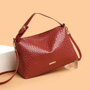 Elegant deep red woven Boston handbag with gold hardware on minimalist backdrop