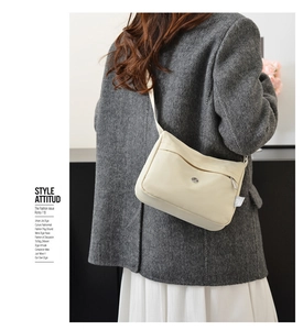 Detail view of stylish beige nylon crossbody bag worn by model in casual grey suit