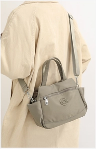 Detail of grey-green nylon crossbody bag with adjustable straps and multi-pocket design