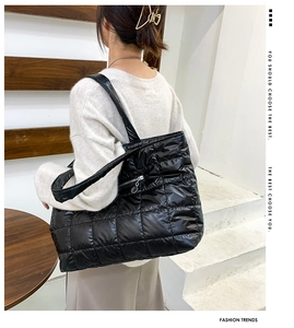 Detail of black glossy quilted tote bag with silver metal zipper side pocket view