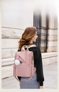 Pink waterproof nylon backpack for women with white pompom charm and anti-theft design