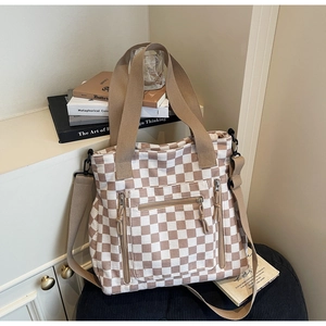 Detail of checkered tote bag showing multiple zipper pockets and wide shoulder straps