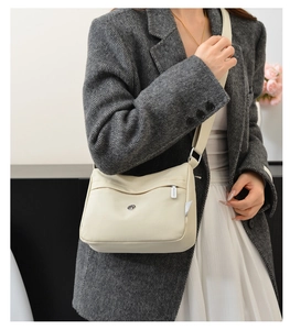 Detail showing beige nylon crossbody bag with zipper pocket and adjustable strap