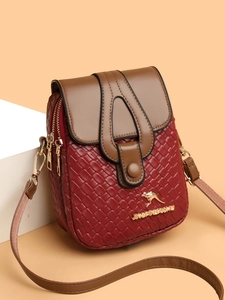 Detail of burgundy woven crossbody bag featuring dual zippers and golden logo