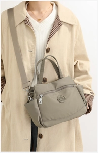 Detail view of khaki nylon crossbody bag showing water-resistant fabric and metal zipper