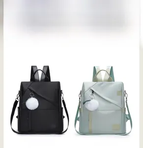 Detail view of water-resistant oxford fabric backpacks in black and green with pom pom charm