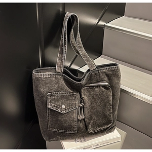 Detail of dark grey washed denim tote with front cargo pockets and silver button flap
