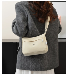 Detail of beige nylon crossbody bag showing multi-pocket structure and wide strap
