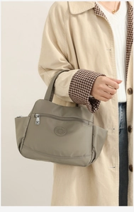 Close-up of khaki nylon shoulder bag with zip pockets and circular logo detail