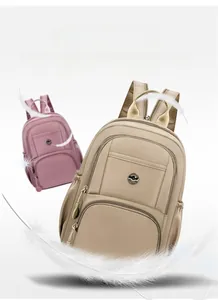 Detail of lightweight nylon travel backpacks in beige and pink with feather design