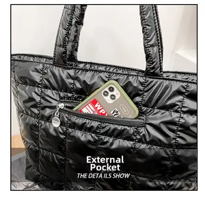Detail showing the external zipper pocket on a black quilted tote bag with a smartphone